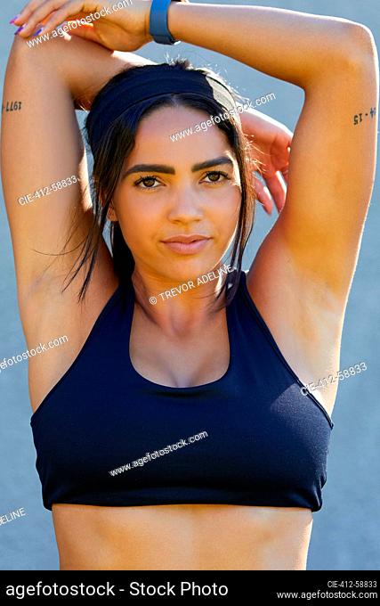 Portrait young female track and field athlete in sports bra stretching