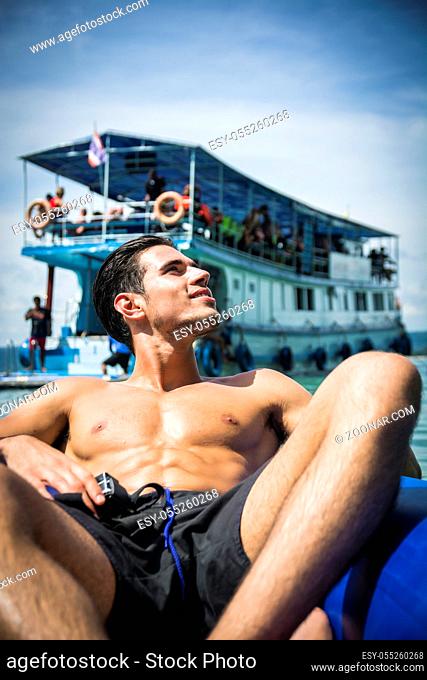 Rear view of a man on a raft relaxing drifting along the river in Phuket, Thailand