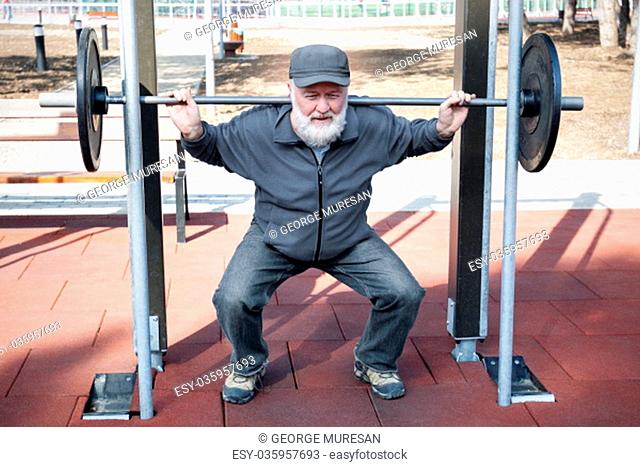An old man lifting weights in the fitness park