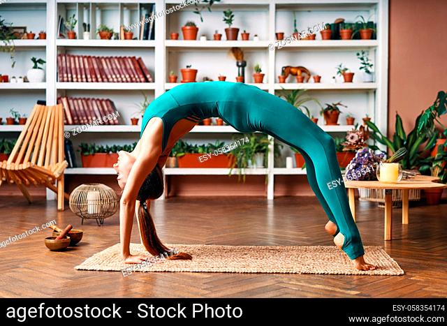 Young woman practicing yoga doing bridge pose, Setu Bandha Sarvangasana at home. Wellness and healthy lifestyle concept