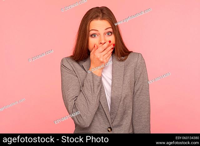 I won't tell anyone. Portrait of frightened intimidated woman in business suit keeping her mouth closed with hand, wondered about secret, terrified to speak