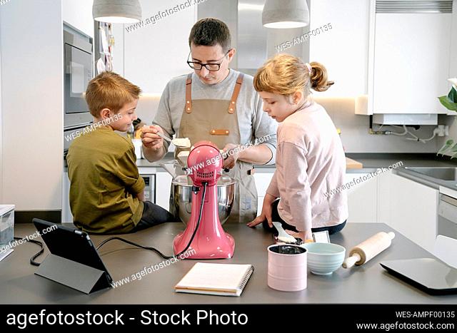Father preparing food while standing by children at home