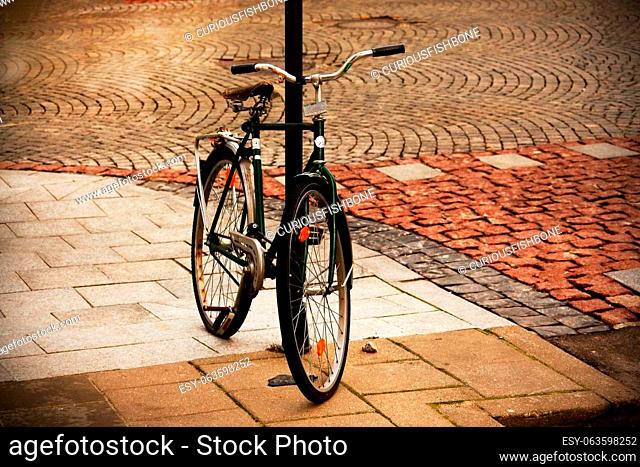 Old bicycle parked on old town sidewalk with white and red road tiles
