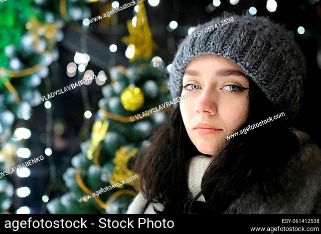 young beautiful happy smiling girl posing Christmas tree on background. Model wearing stylish clothes. Happy New Year with lights