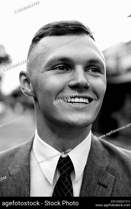Portrait of young businessman wearing suit in the streets outdoors in black and white