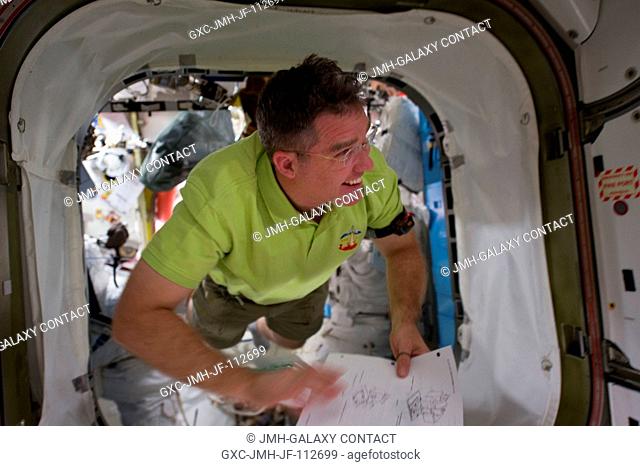 NASA astronaut Steve Bowen, STS-133 mission specialist, floats through a hatch on the International Space Station while space shuttle Discovery remains docked...