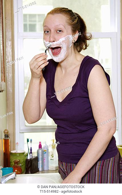 Woman in bathroom shaving like a man for fun