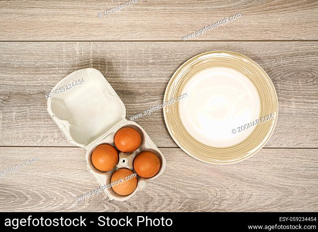 four eggs in a carton box on the wooden table