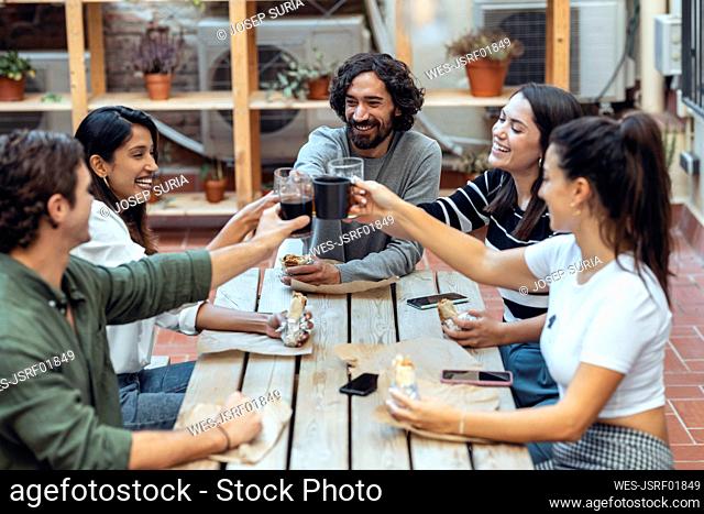 Happy businessmen and businesswomen toasting drinks at cafeteria