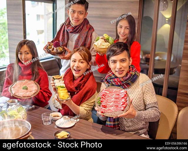 young group showing wide variety foods in hot pot restaurant