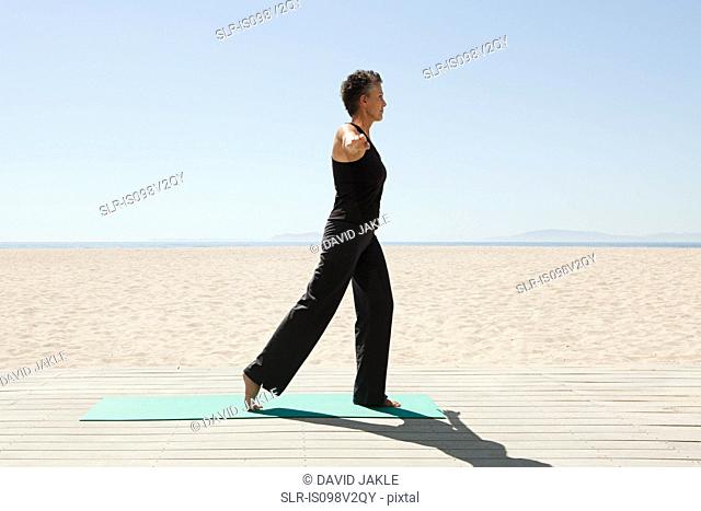 Senior woman doing yoga on beach