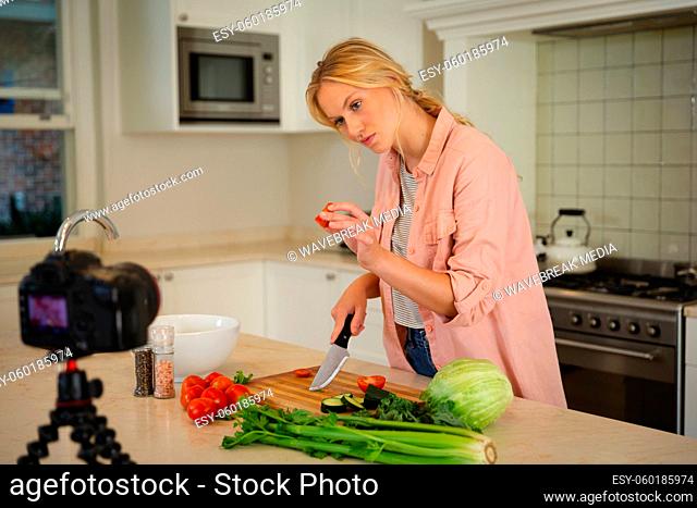 Caucasian woman in kitchen preparing food, holding vegetable to camera, making cooking vlog