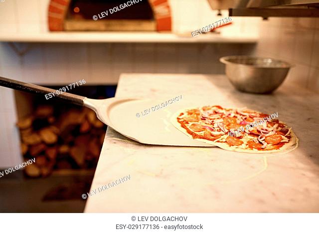 food, italian kitchen, culinary, baking and cooking concept - peel taking pizza off table at pizzeria