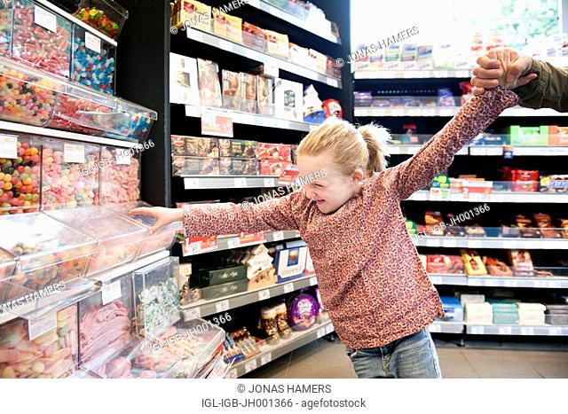 A little girl tries to grab some candies
