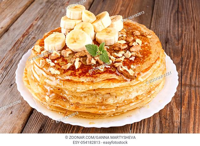 A pile of pancakes with honey , banana and nuts. Healthy breakfast. Shrovetide. Russian pancakes