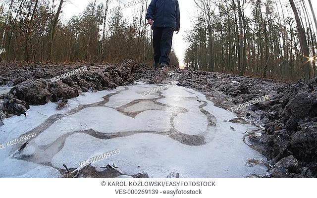 Walking and braking the ice on the forest dirt road near Lublin, Lubelskie, Poland