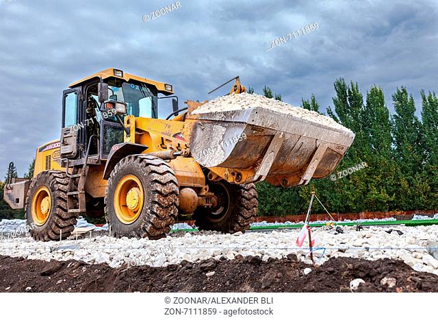 SAMARA, RUSSIA - SEPTEMBER 28, 2014: Heavy bulldozer loading and moving gravel on road construction site