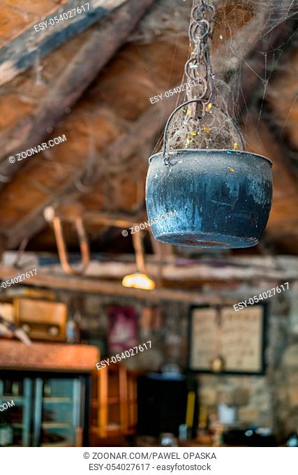 Old pot covered in spider web hanging from the ceiling in an old farm building