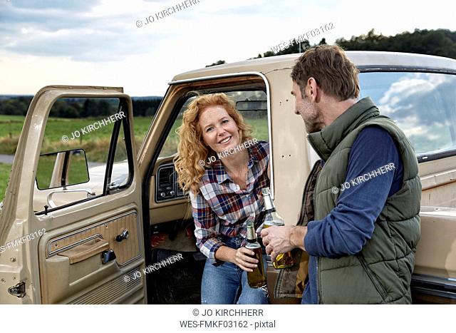 Couple at pick up truck with beer bottles