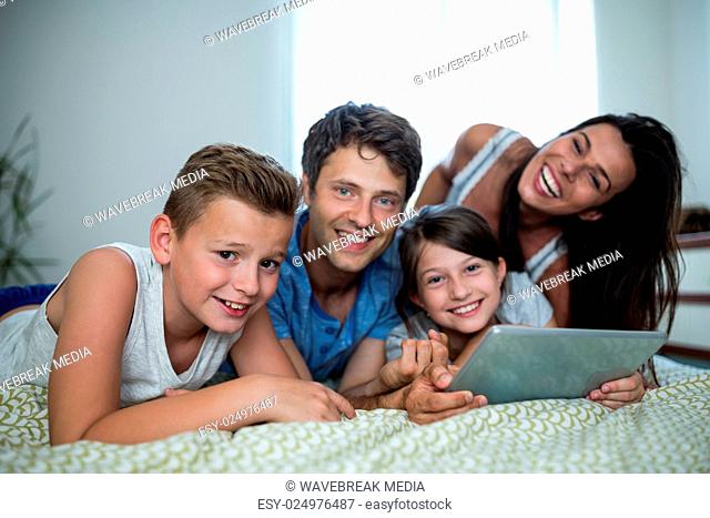 Happy family using digital tablet in bedroom at home