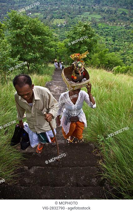 BALINESE DEVOTEES climb stairs to a remote Hindu temple located on a hill above a agriculture valley near PEMUTERAN - BALI, INDONESIA - 12/12/2010