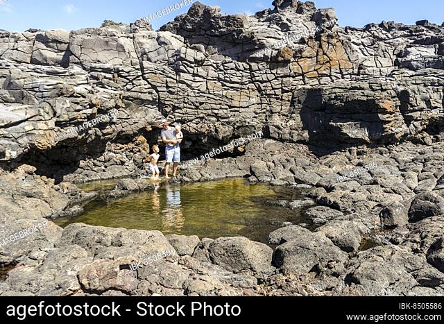Father with two small sons enjoys his vacation by Charcones natural pools in Lanzarote, Canary Islands, Spain, Europe