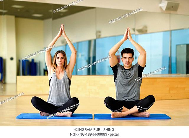 Young woman and man practicing yoga indoors. Two people doing exercises