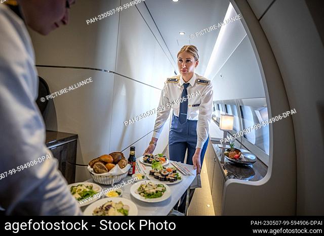04 May 2023, Brandenburg, Schönefeld: Flight attendants serve sushi as an appetizer on board the Airbus A350-900 ""Konrad-Adenauer"" of the BMVg's Special Air...