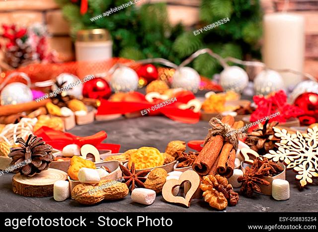 Christmas and new year celebration table decoration background with garland, cookies, spicies, cinnamon, pine cones, wallnuts and candle in cup and other xmas...