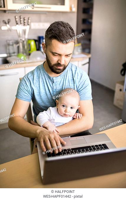 Father with baby son using laptop at home
