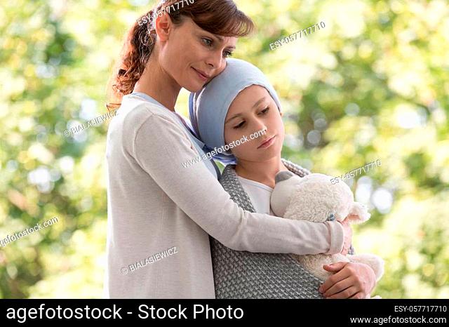 Mother hugging sad daughter with cancer