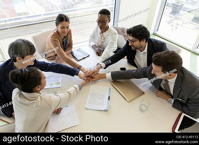 Business people joining hands in conference room meeting
