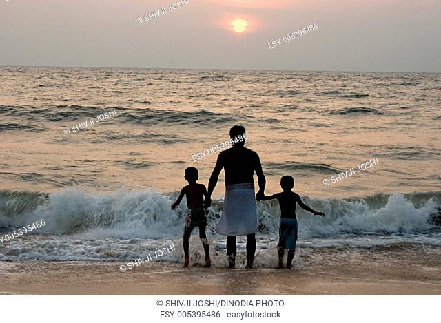 Father with his sons enjoying sunset at cherai beach in cochin ; Kerala ; India MR704