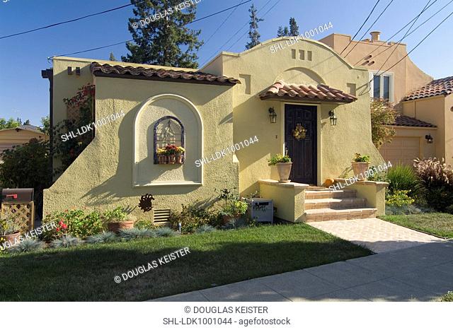 Front exterior one story Spanish style house with potted plants