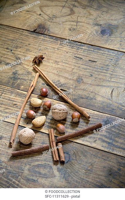 A Christmas tree made from nuts, anise stars and cinnamon sticks on a wooden table