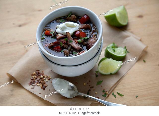 A bowl of chilli con carne with peppers and sour cream