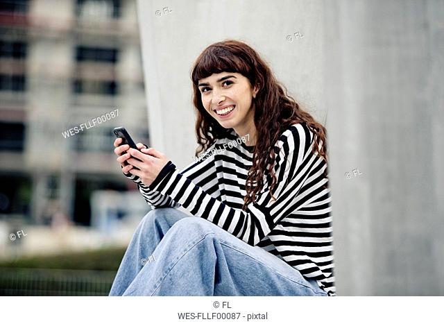 young woman wearing striped shirt, using smartphone
