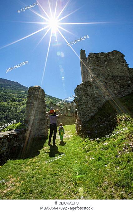 Tourists walk among the ruins of Castle Visconti Venosta. Grosio. Province of Sondrio. Valtellina. Lombardy. Italy. Europe