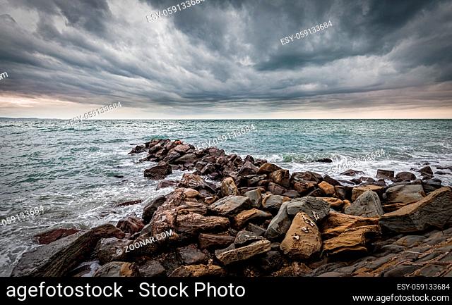 Waves of the Adriatic Sea crashing over an artificial cliff under stormy sky