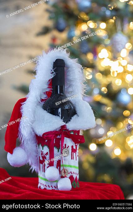 A red wine and bottle with blurred bokeh lights on Christmas tree in background. Christmas gift, Holiday, present concept with copy space Merry Christmas