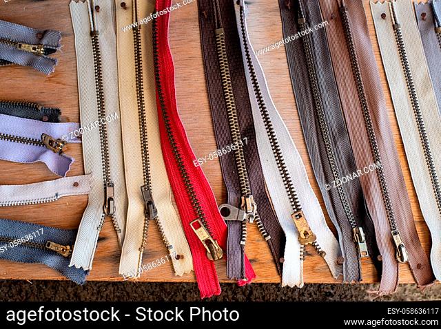 Variety of old worn used cloth zippers on a wooden board