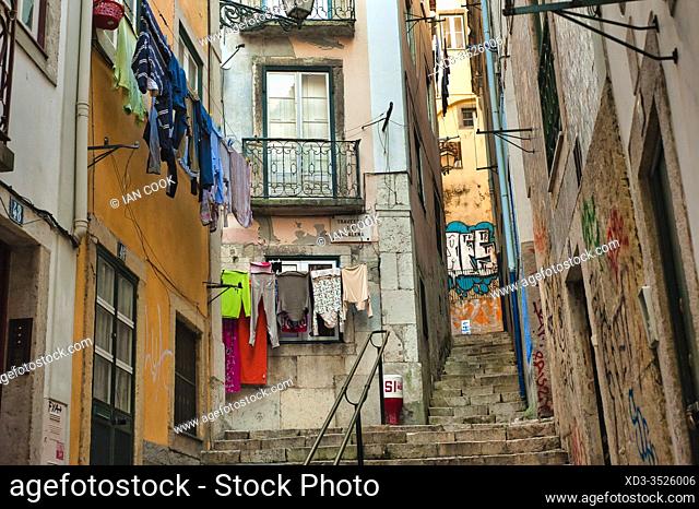 narrow streets with laundry hanging to dry and graffiti in Alfama neighbourhood, Lisbon, Portugal