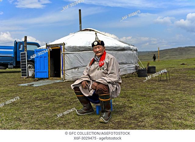 Elderly male nomad in traditional dress sitting in front of his yurt, Mongolia