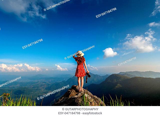 Woman hand holding camera and standing on top of the rock in nature. Travel concept
