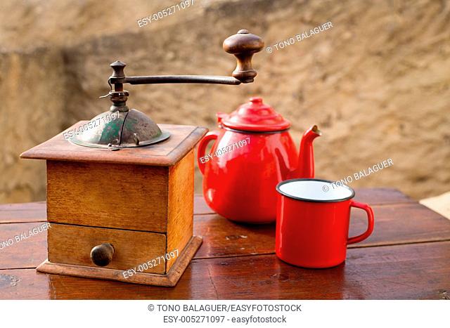 retro old coffee grinder with vintage teapot and red cup