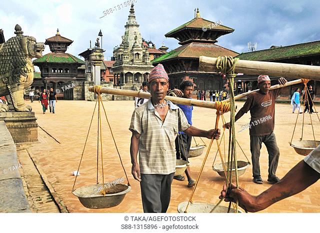 Workers walk by with balance soil carrier in Durbar Square UNESCO World heritage site