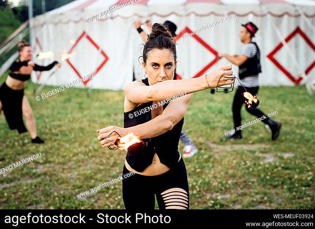 Female acrobat practicing with fire equipment outside circus tent