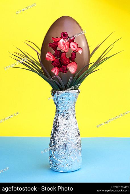 Chocolate Easter egg and decoration on vibrant blue and yellow background