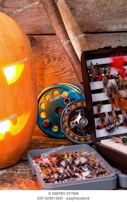 halloween pumpkin head with fly-fishing tackles on wooden boards background