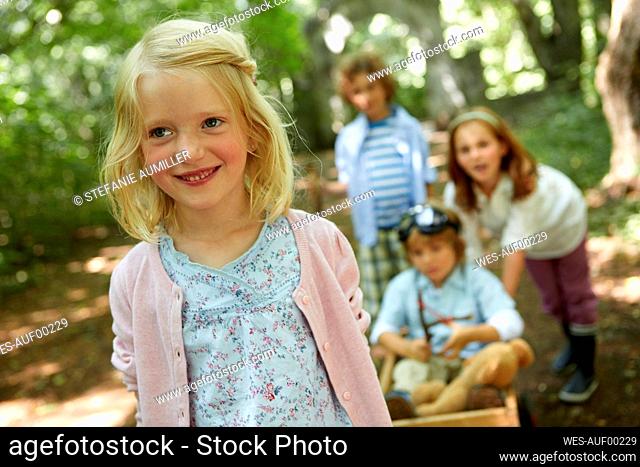 Children with hand cart playing in forest